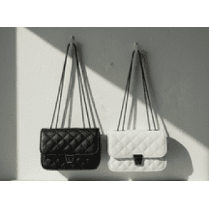 Black and white quilted flap bags with silver chain straps and turn-lock clasps hanging on a wall.